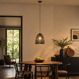 Small black pendant light above wooden dining table in warm dining area