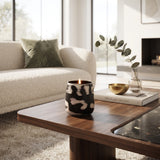 Small black and cream patterned candle holder styled on a wooden coffee table