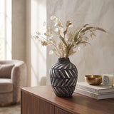 Small dark grey ceramic vase with carved pattern and decorative dried stems