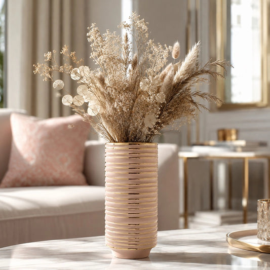 Small blush pink ribbed ceramic vase with neutral dried flowers on a marble table