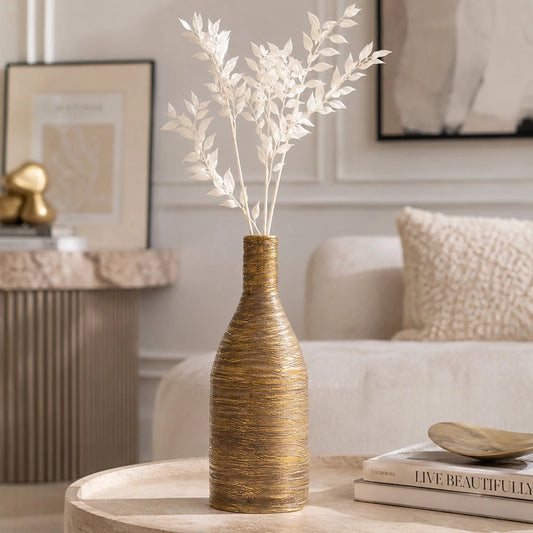 Small gold textured ceramic vase with white dried foliage displayed on a coffee table