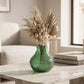 Small green textured glass vase with dried botanical stems styled on a marble coffee table