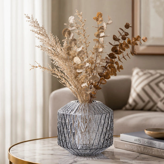 Small grey textured glass vase with dried foliage displayed on a living room side table