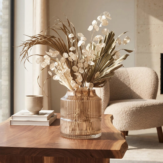 Small grey ribbed glass vase with dried botanical stems styled on a wooden side table