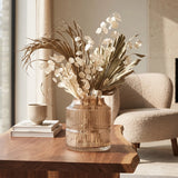Small grey ribbed glass vase with dried botanical stems styled on a wooden side table