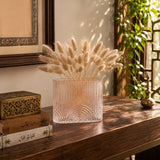 Small pink textured glass vase with dried bunny tail stems displayed on a wooden console table