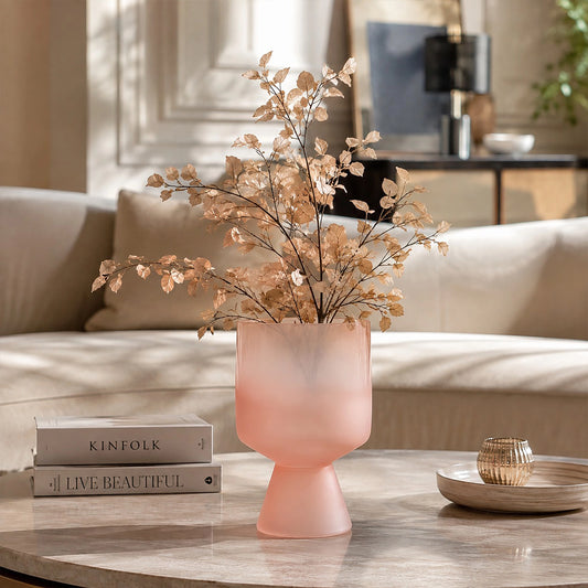 Small pink frosted glass vase with decorative dried foliage styled on a coffee table