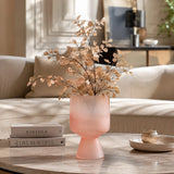 Small pink frosted glass vase with decorative dried foliage styled on a coffee table