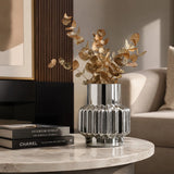 Small silver ribbed decorative vase with dried foliage styled on a marble coffee table