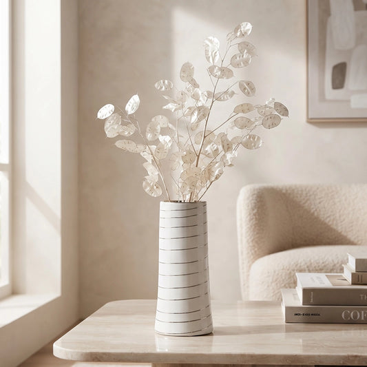 Small white ceramic vase with subtle line detail and decorative white dried stems