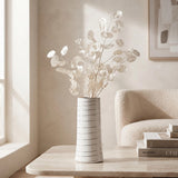 Small white ceramic vase with subtle line detail and decorative white dried stems