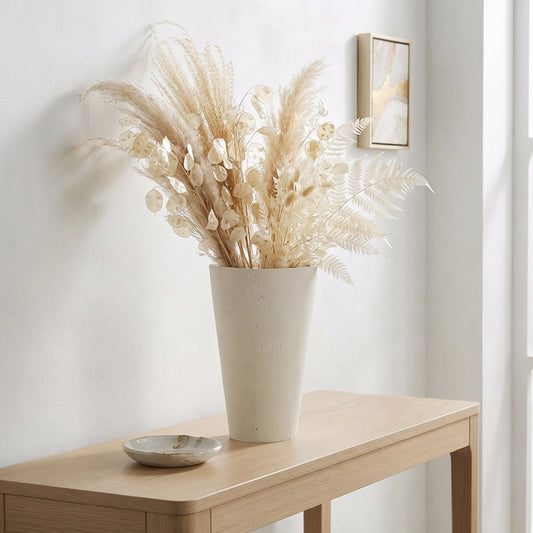 Small white ceramic flower vase with neutral dried stems displayed on a wooden console table