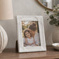 Small white photo frame with decorative border on marble table
