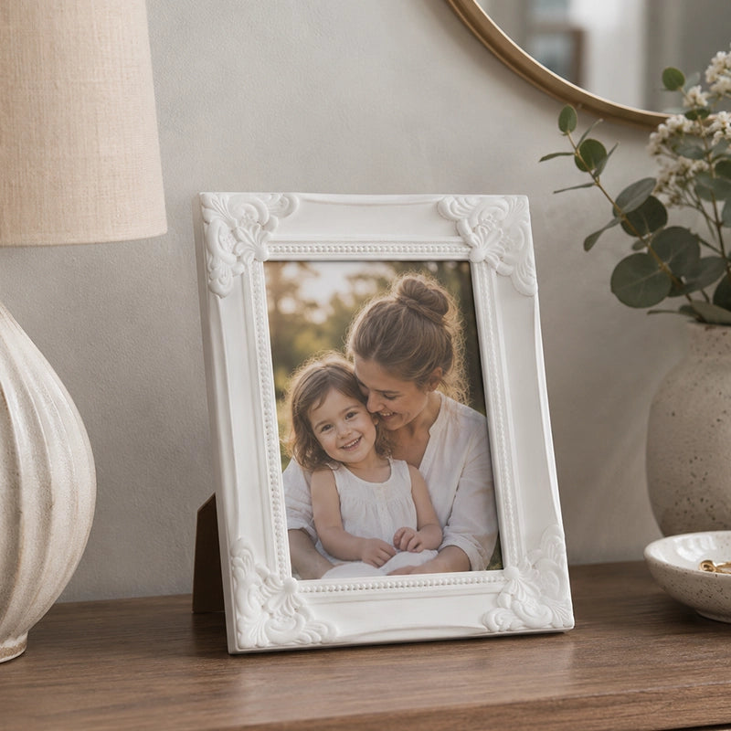 Small white photo frame with decorative border on marble table