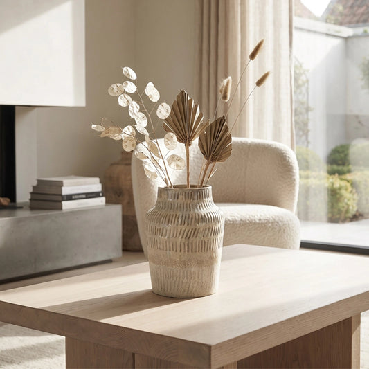 Small white textured ceramic vase with dried botanical stems styled on a wooden coffee table