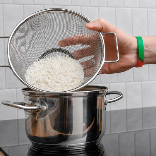Stainless-steel mesh strainer draining cooked rice over a saucepan