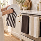 Black white and grey striped cotton kitchen tea towels hanging on an oven door handle