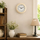 Vintage cream wall clock above side table with lamp, books and vase