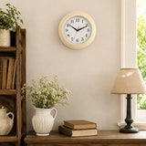 Vintage cream wall clock above side table with lamp, books and vase