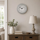 Vintage grey round wall clock above side table with lamp and vase