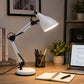White adjustable desk lamp on wooden office desk with notebook and laptop