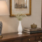 White curved ceramic vase with delicate white flowers styled on a wooden console table