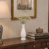 White curved ceramic vase with delicate white flowers styled on a wooden console table