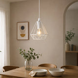 White pendant light with wire shade hanging above wooden dining table