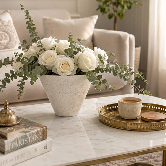 White round textured vase filled with white roses and eucalyptus on a marble coffee table