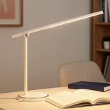 White touch lamp with slim LED bar on desk beside open book