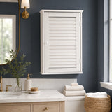 White wall cabinet with single shutter door above bathroom vanity and towels
