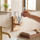 Wooden wall-mounted toothbrush holder with toothbrushes fitted above a bathroom basin