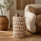 Round side table with natural wood slice pattern beside cream armchair