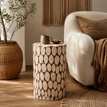 Round side table with natural wood slice pattern beside cream armchair