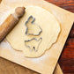 6 piece animal shape cookie cutter set including rabbit and cat on rolled dough with a rolling pin
