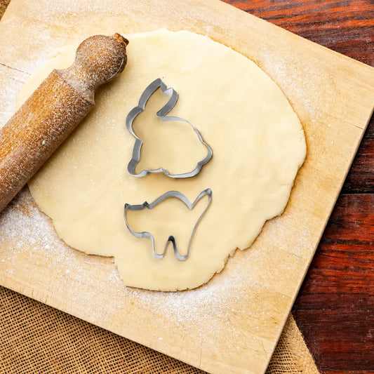 6 piece animal shape cookie cutter set including rabbit and cat on rolled dough with a rolling pin
