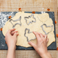 Hands cutting animal shape cookies from rolled dough with a metal cookie cutter set