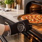 Black single oven glove with vintage Cook stamp design worn while sliding a pepperoni pizza out of the oven