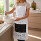 Woman wearing a white cotton kitchen apron with black ink splatter print and solid black front pocket while whisking in a modern home kitchen