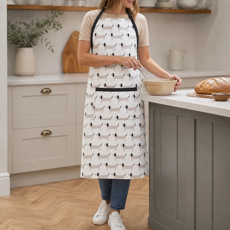 woman wearing black and white kitchen apron with dog print while mixing in bowl, novelty dog design cotton apron for women