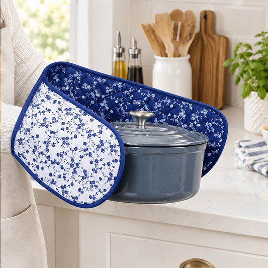 Blue and white floral double oven gloves used to hold a grey cast iron pot on a kitchen countertop