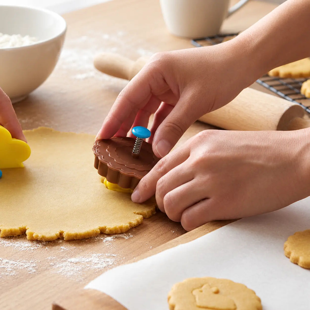 Hand using a flower and rabbit cookie cutter stamp to press a design into cookie dough