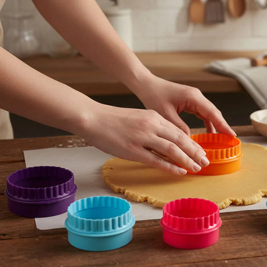 Hands pressing a colorful round cookie cutter into rolled dough with nested cutters nearby