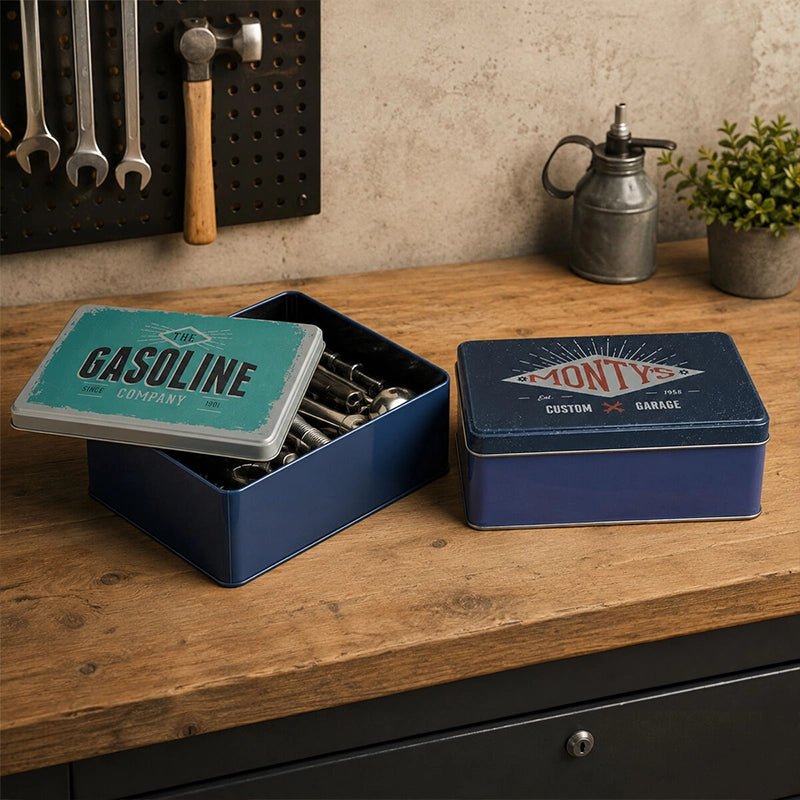 Navy blue metal storage tin with lid open showing kitchen utensils on a wooden countertop