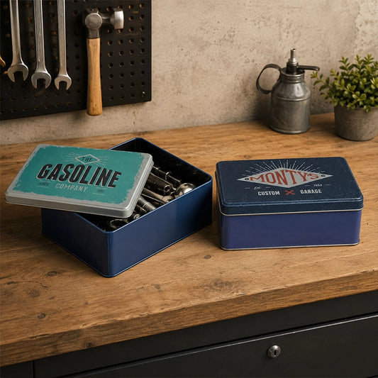Navy blue metal storage tin with lid open showing kitchen utensils on a wooden countertop