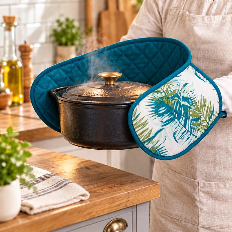 Teal tropical print cotton double oven gloves used to lift a black dutch oven on a kitchen countertop