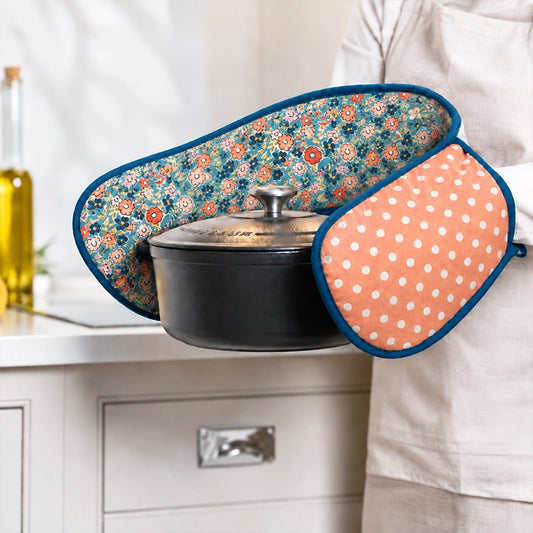 Coral polka dot floral print double oven gloves with teal trim used to hold a black casserole pot