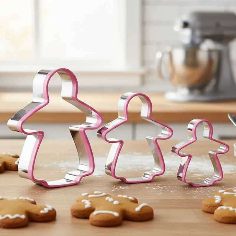 Three gingerbread lady cookie cutters in small, medium and large sizes with baked cookies in a kitchen
