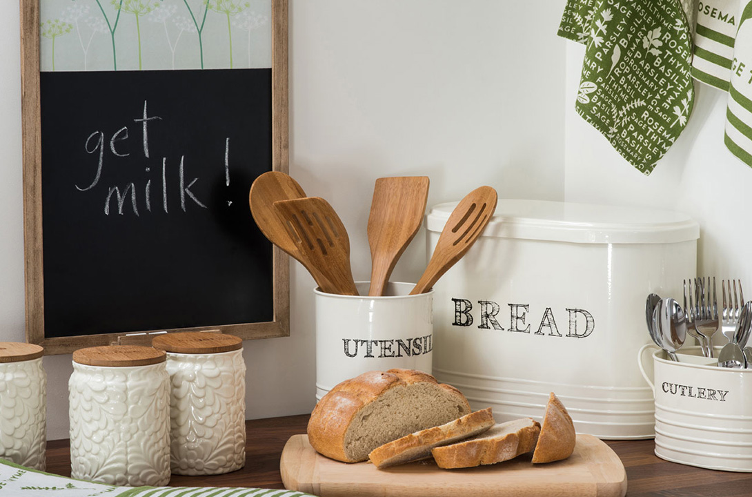 Kitchen accessories with wooden utensils, ceramic bread bin, cutlery holder, storage jars and chopping board