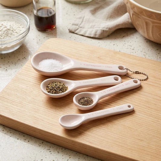 Ceramic kitchen measuring spoons set of 4 with spices on wooden cutting board